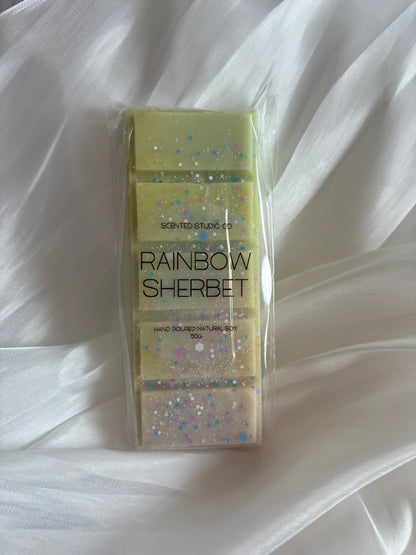 Hand-poured Rainbow Sherbet soy wax melt snap bar in a recyclable pouch on top of scrunched fabric for aesthetic appeal